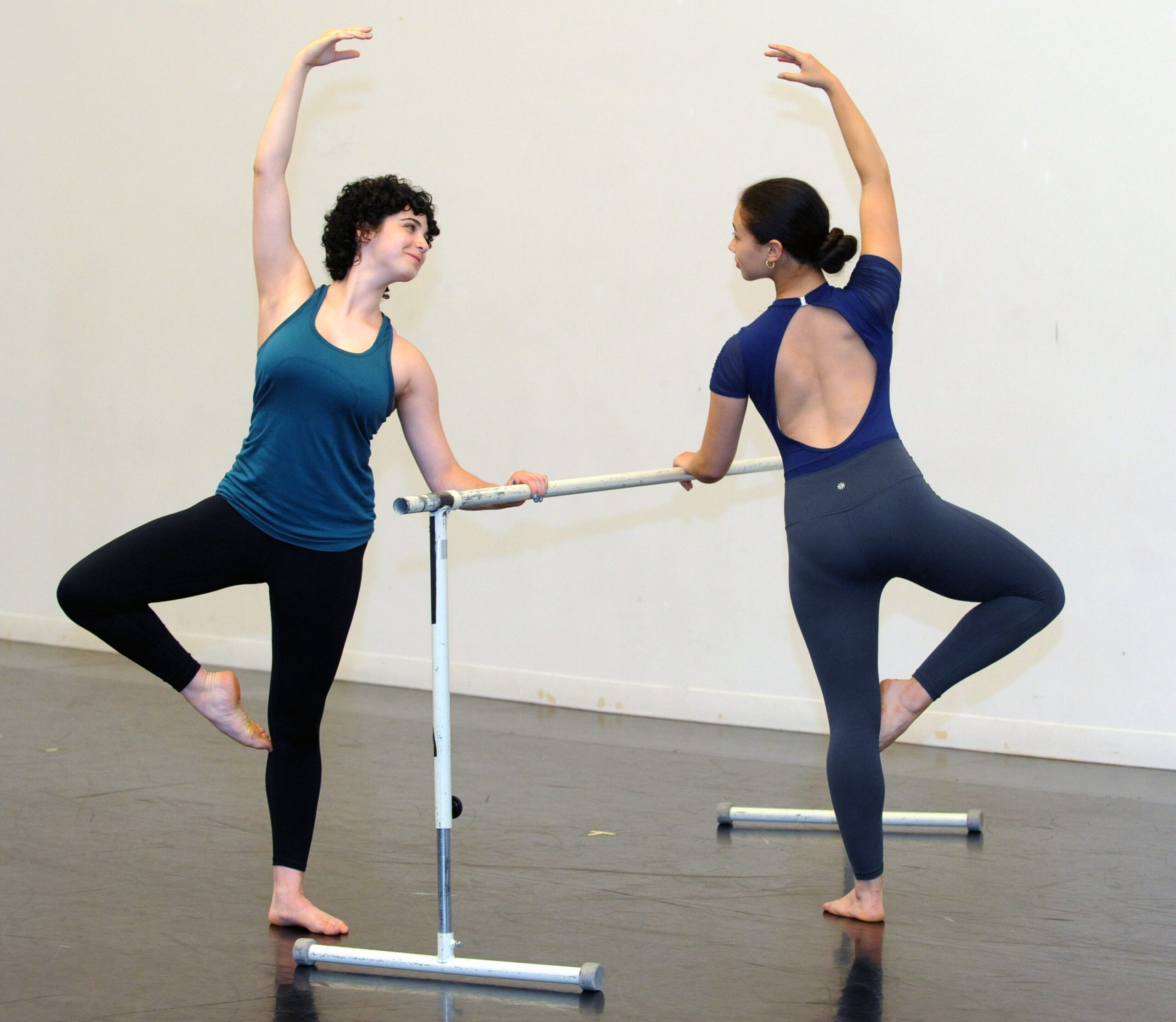 Two teen Taylor School dancers practicing their passe at a ballet barre during a dance class