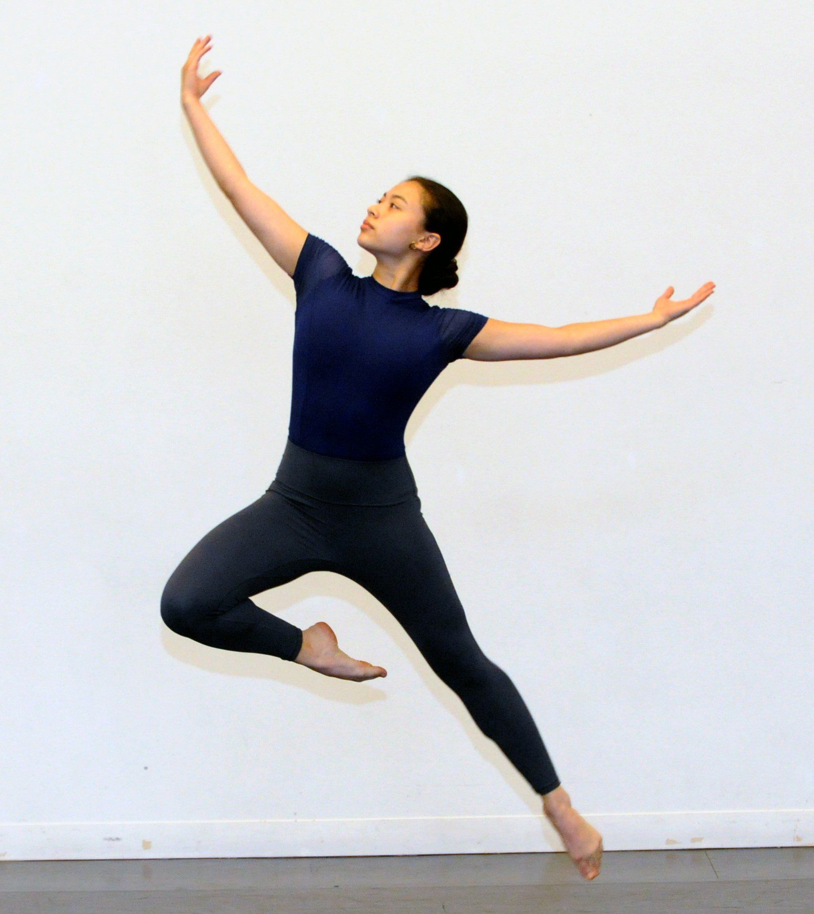 Teen Taylor School dancer leaping with arms extended during a modern dance class